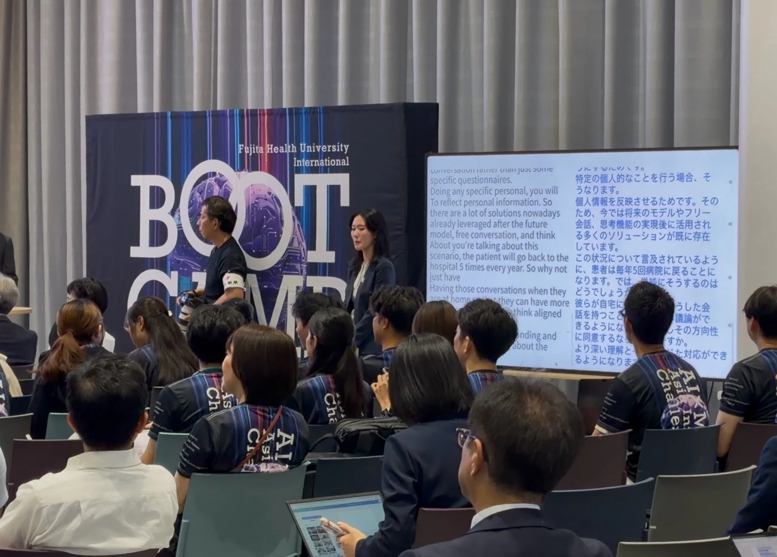 AI×MedTechの登壇者と、英語および日本語のリアルタイム字幕を来場者に表示する大型画面。