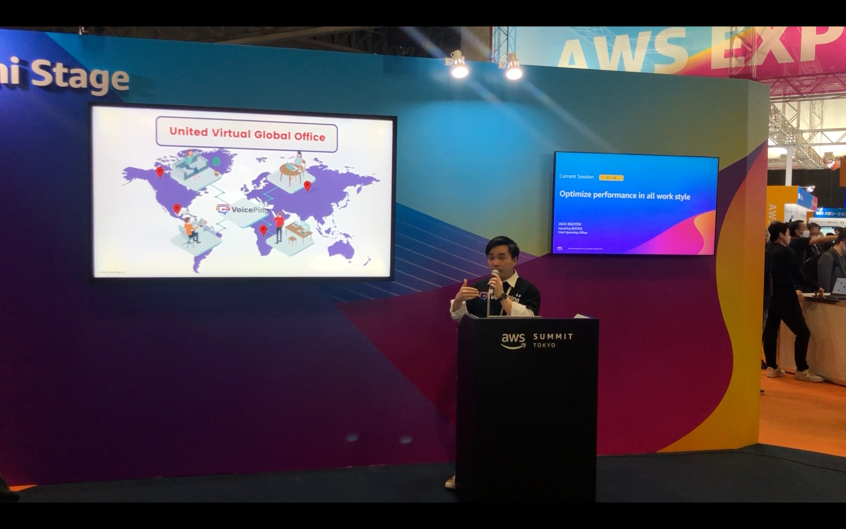 AWS Summit Tokyoのミニステージで、世界各地のチームをつなぐ図を背に講演するVoicePing COOのJack Nguyen