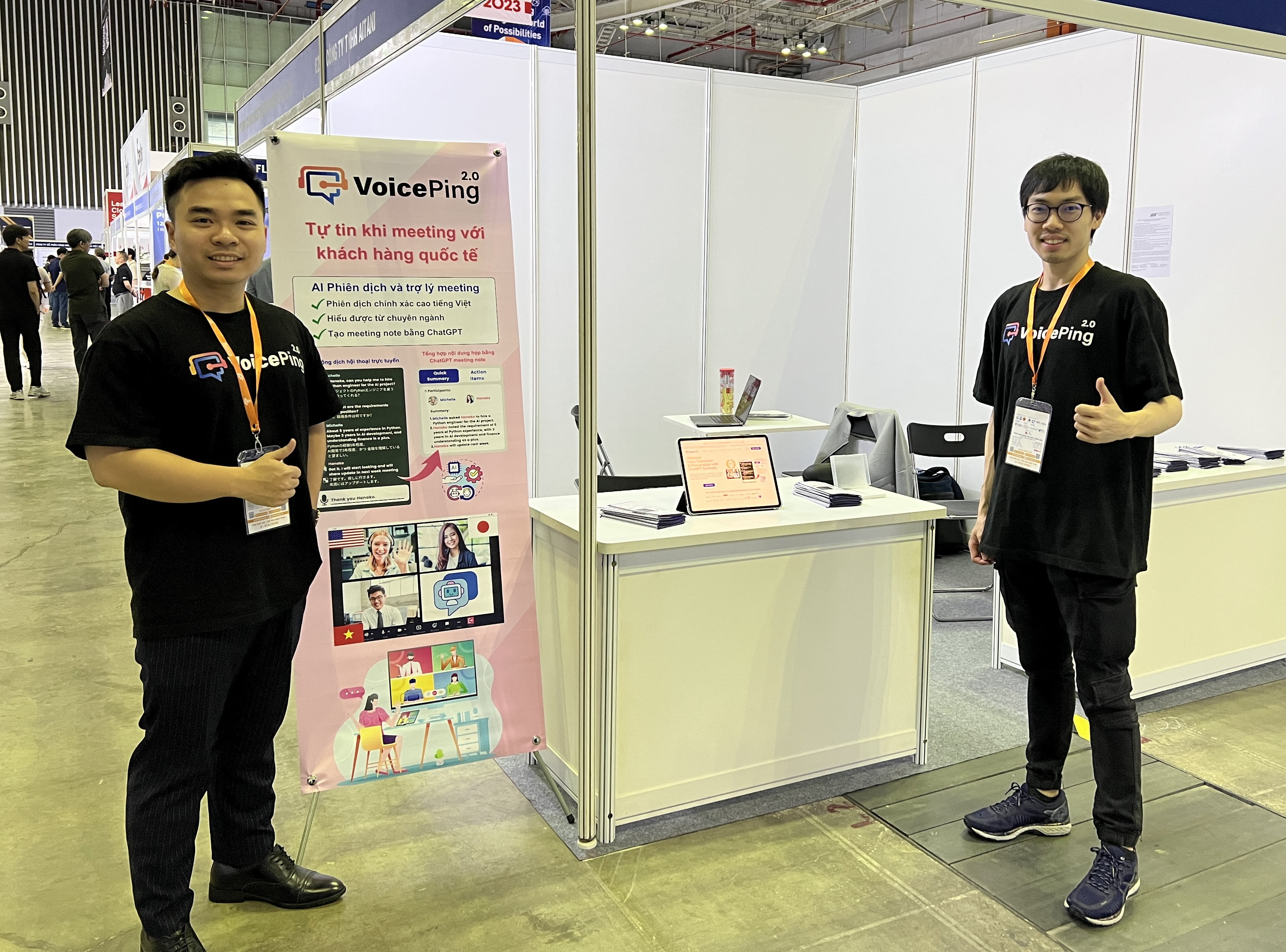 Vietnam ICTCOMM 2023のVoicePingブースで、ベトナム語の説明パネルを挟んで立つメンバー2名