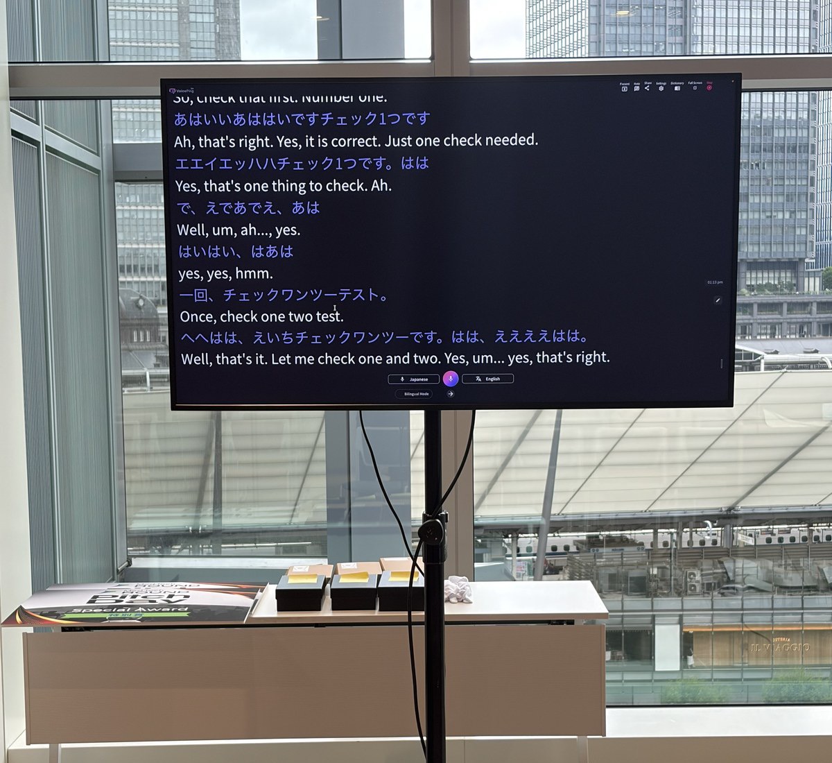 会場に設置された VoicePing の翻訳画面。ライブの書き起こしが表示されている。