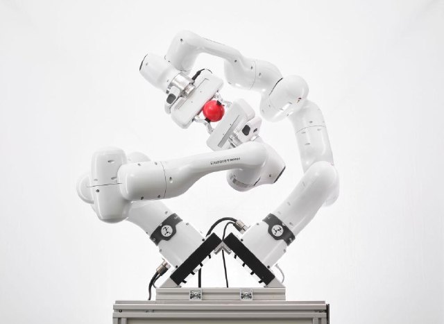 傾斜した架台に取り付けられ、赤い物体を一緒に持つ2台のFranka Research 3。各アームは7自由度。