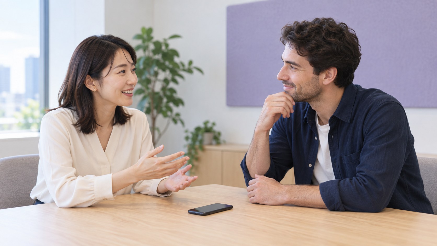 スマートフォンをテーブルに置いて話す2人。対面翻訳の利用イメージ