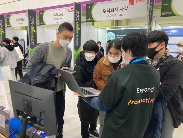 音声翻訳機能で韓国人来訪者にVoicePingについて説明する日本人スタッフの様子